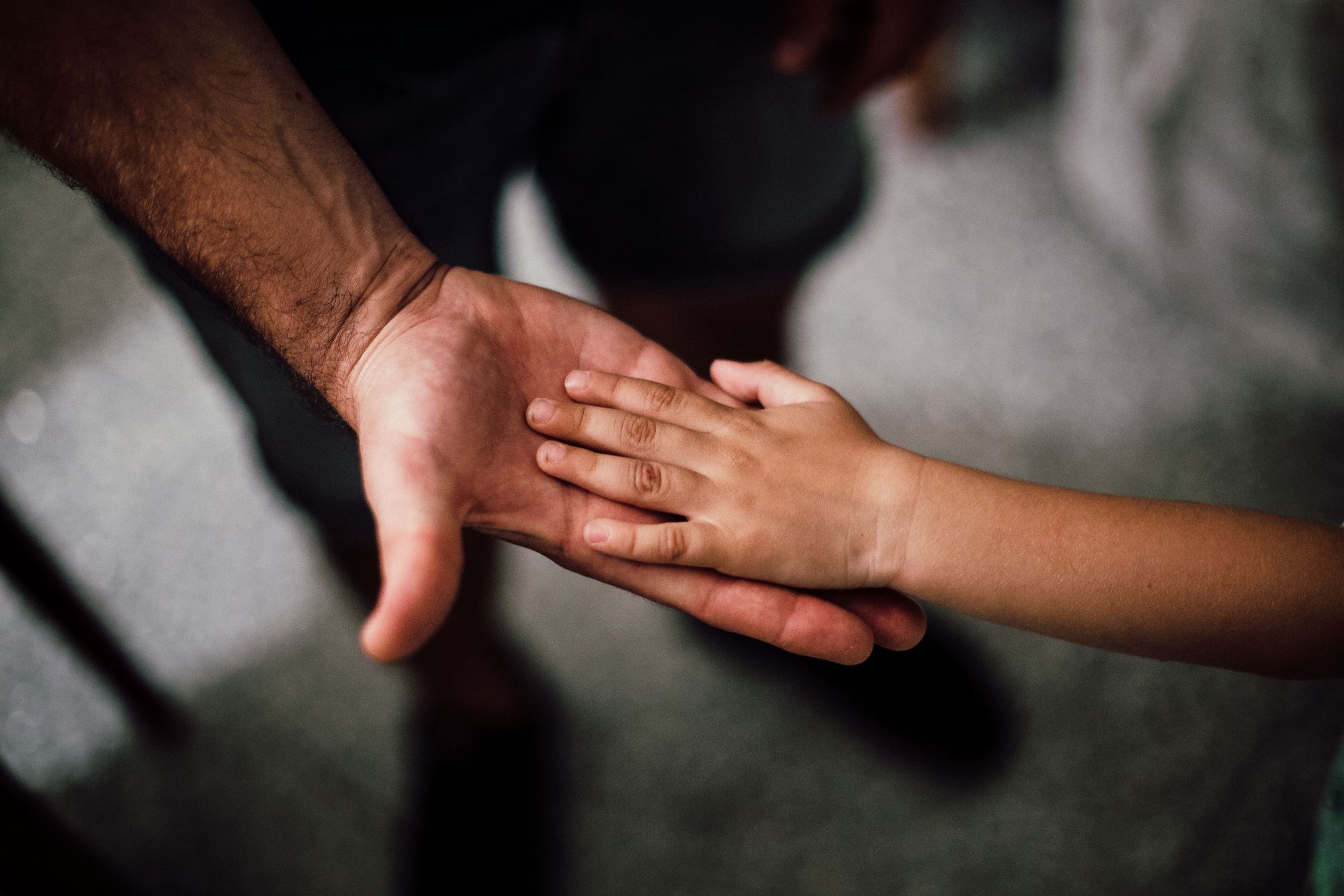 An adult hand holding a child’s hand